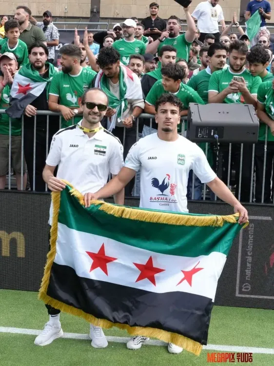 أحد المشجعين يرفع العلم السوري بجوار الملعب.